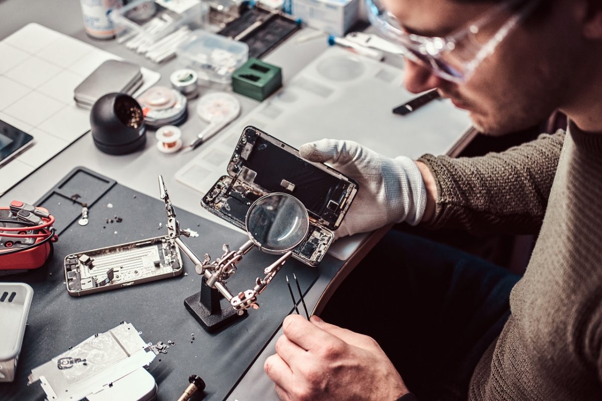 Technicien Électronique réparation smartphone endommagé dans l'atelier